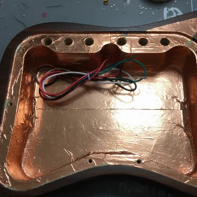 Electric guitar control cavity shielded with copper tape, wiring neatly arranged, ready for components.